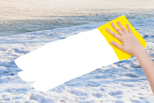 Hand deletes white snow by yellow rag — Stockfoto