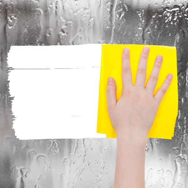 Hand deletes rainy water on window by yellow rag — Zdjęcie stockowe