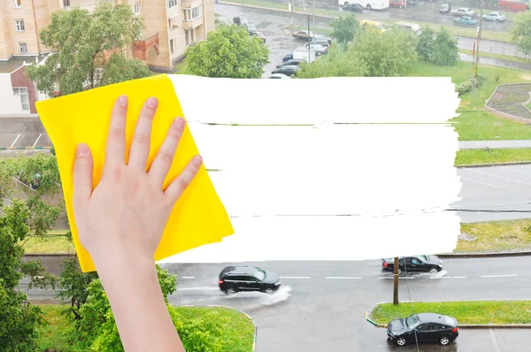 Hand deletes rain on street by yellow rag — Zdjęcie stockowe