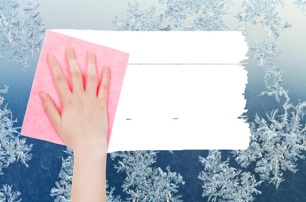 Hand deletes winter snowflake on window by pink rag — 图库照片