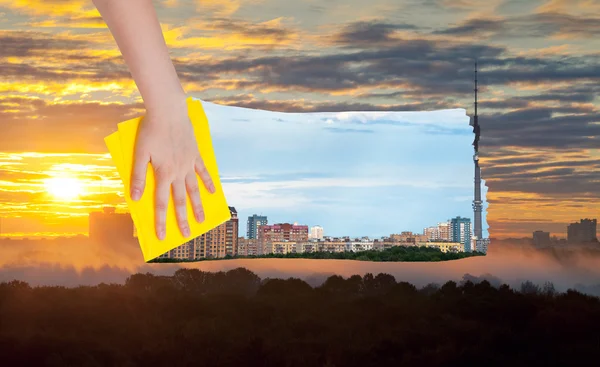 Hand tar bort gula soluppgång över staden med en trasa — Stockfoto