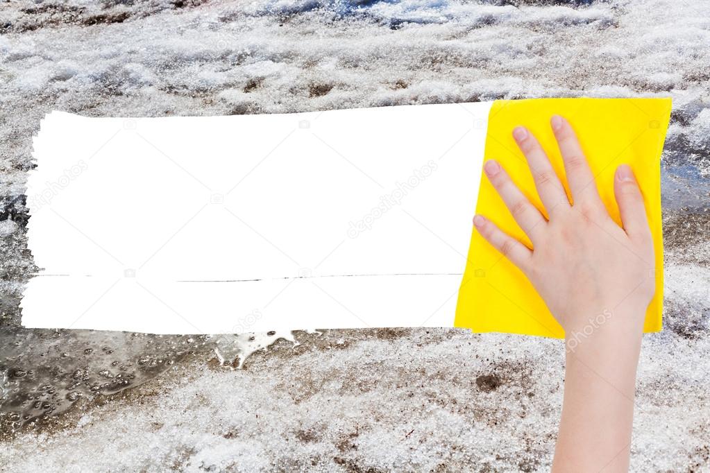 hand deletes melting snow by yellow rag