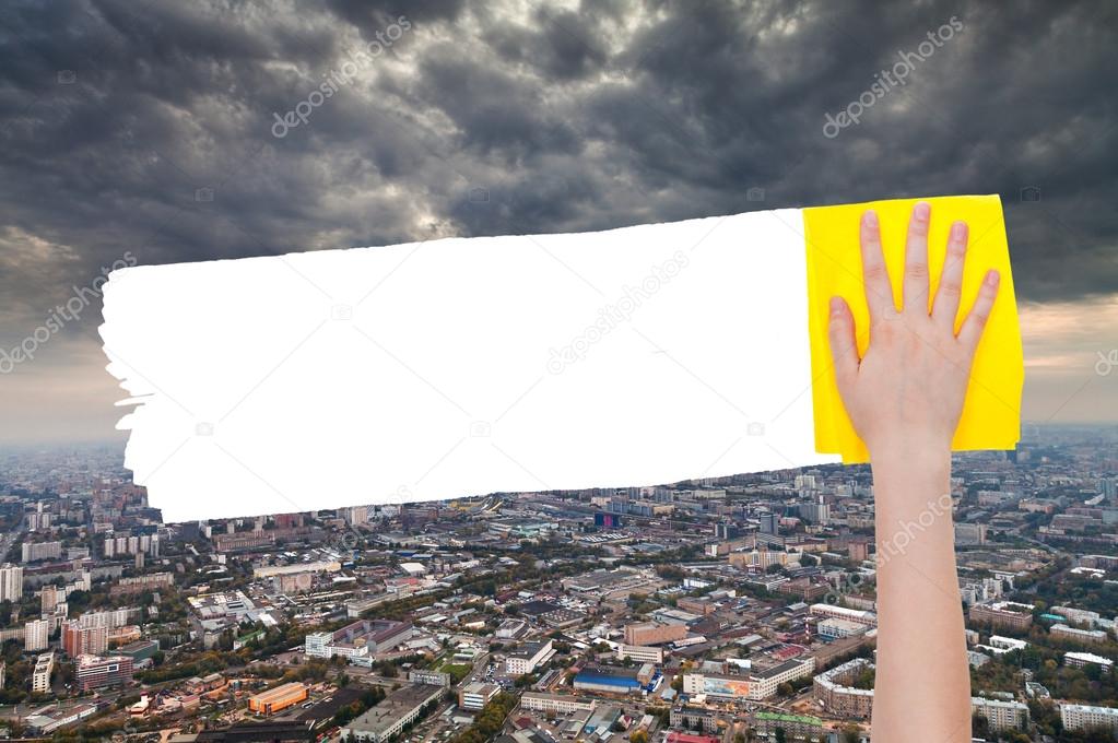 hand deletes storm clouds over city by yellow rag