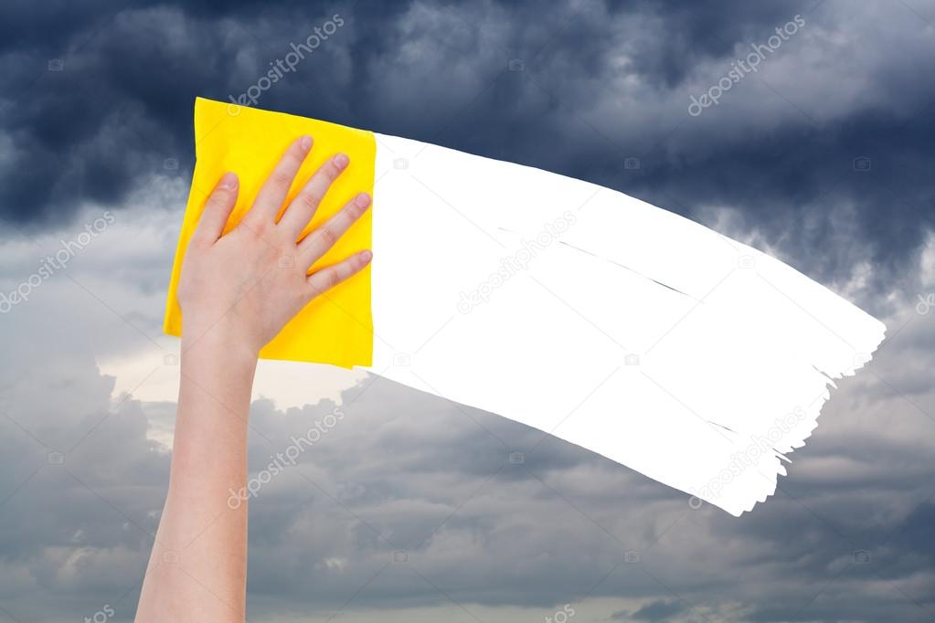 hand deletes overcast sky by yellow rag