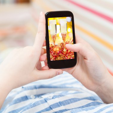 woman touches smartphone with gold Xmas still life