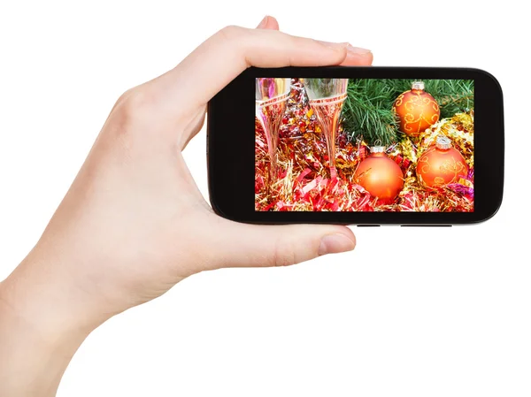 Mano sostiene el teléfono móvil con la naturaleza muerta de Navidad — Foto de Stock