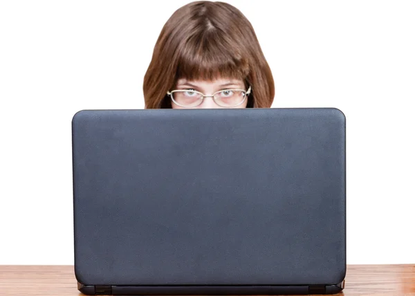 Meisje met bril kijkt over cover van laptop — Stockfoto