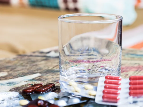 Leeg glas en stapel van pillen close-up op tafel — Stockfoto