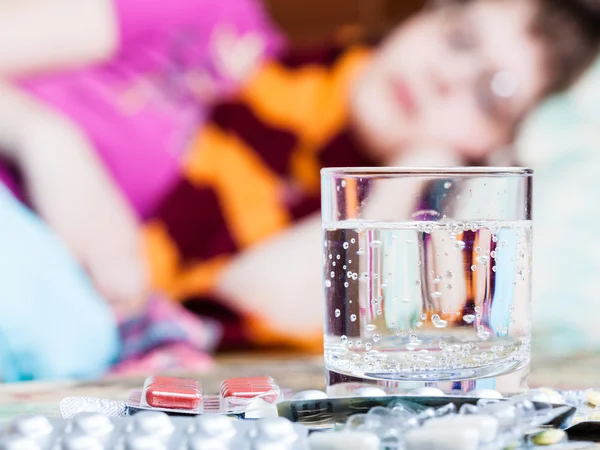 Vidrio y pastillas en la mesa de cerca y la mujer enferma — Foto de Stock