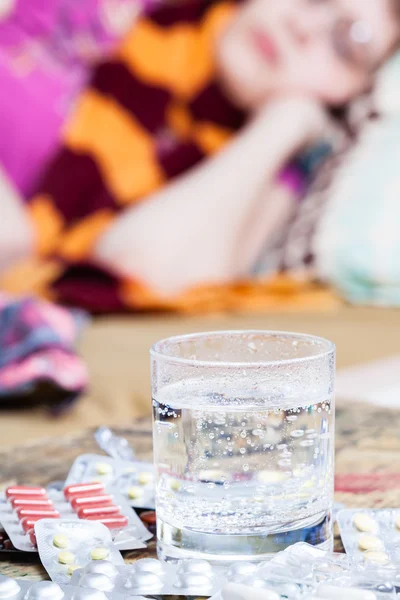 Glas med medikament och hög med piller på tabell — Stockfoto