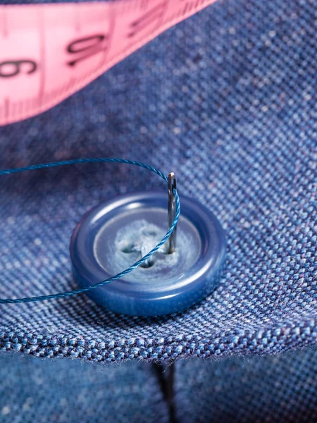 Attaching of button to blue silk suit by needle — Stock Photo, Image