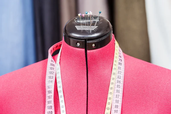 Mannequin with measure tapes and clothes — Stock Photo, Image