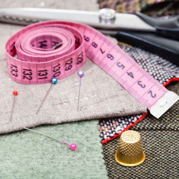 Fita métrica rosa, pinos, dedal, tesouras no tecido — Fotografia de Stock