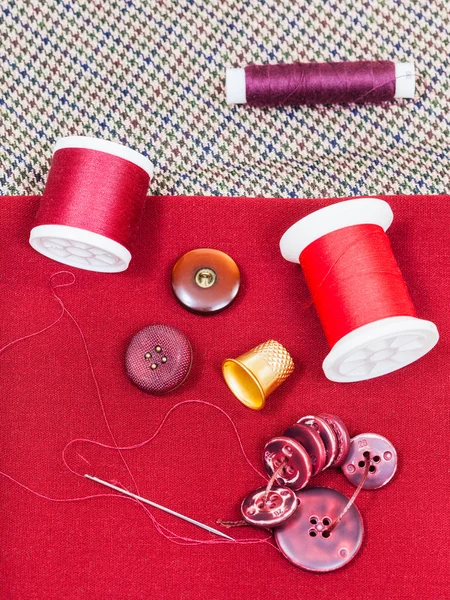 Linha de costura, botões, dedal em pano vermelho — Fotografia de Stock