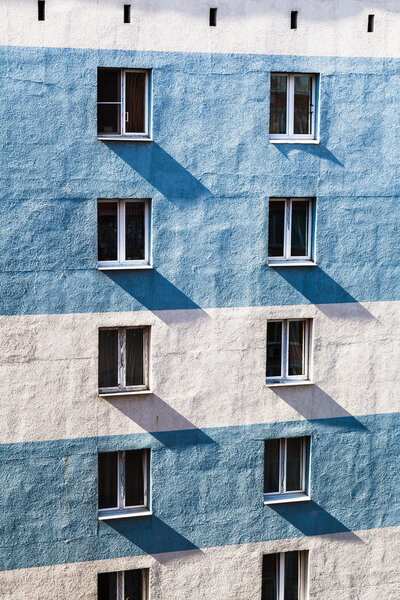 Apartment building wall with windows illuminated by contrasting sunlight in morning