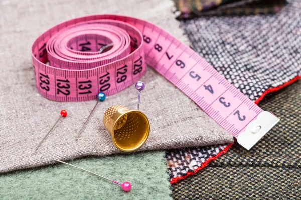 Pink measure tape, pins, thimble on textile — Stock Photo, Image