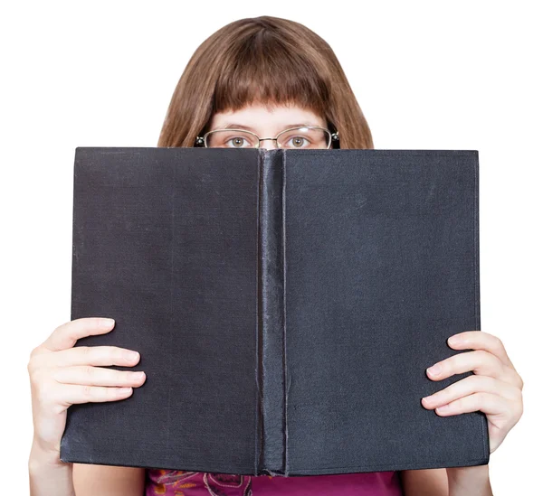 Front view of girl with spectacles looks over book — Stock Photo, Image