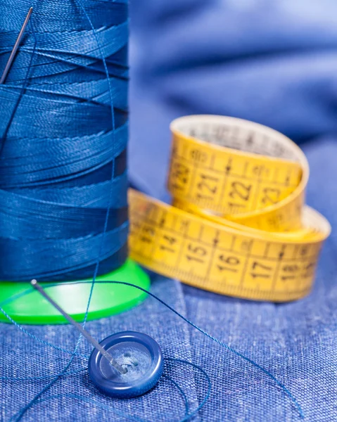 Tråd spolen, knapp, mått band på blå klänning — Stockfoto