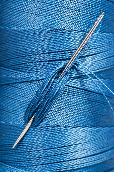 Sewing needle in blue thread spool — Stock Photo, Image