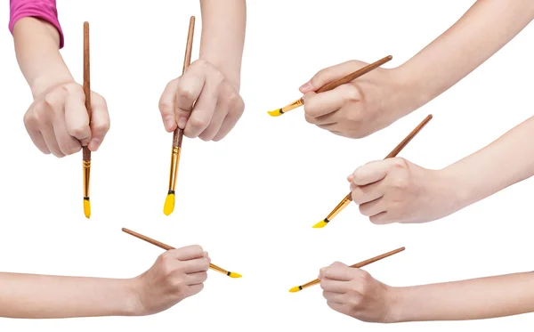 Set of hands with art paintbrushes with yellow tip — Stock Photo, Image