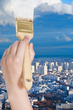 paintbrush paints white clouds over blue city
