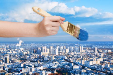 paintbrush paints blue sky over big city