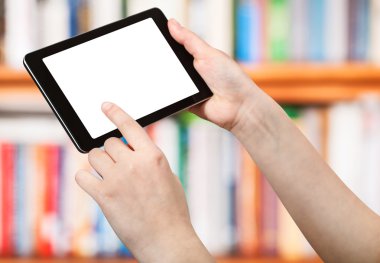 kitap rafları önünde tablet PC'de parmak dokunuyor