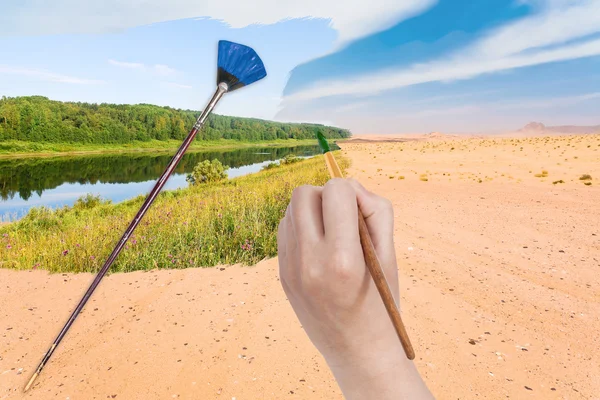 Mano con pinturas al pincel río en desierto de arena — Foto de Stock