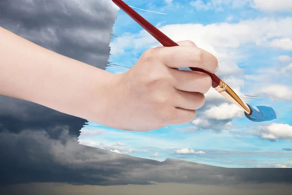 Paintbrush paints blue sky on storm clouds — 图库照片