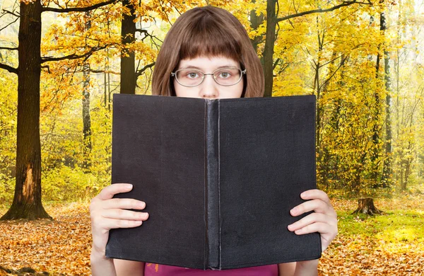 Chica lee libro grande y bosque de otoño —  Fotos de Stock