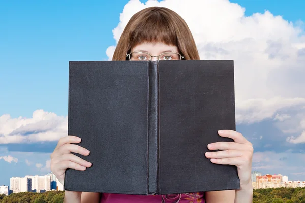 Chica mira sobre gran libro y nube blanca —  Fotos de Stock