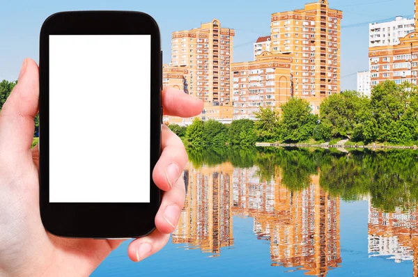 Smartphone und neue Mehrfamilienhäuser am See — Stockfoto
