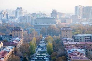 Erivan, Ermenistan - 22 Kasım 2025: Tamanyan Caddesi ve Alexander Spendiaryan Ulusal Akademik Opera ve Bale Tiyatrosu 'nun yukarısında Erivan şehrinin Kaynağı' nda sisli sonbahar alacakaranlığında