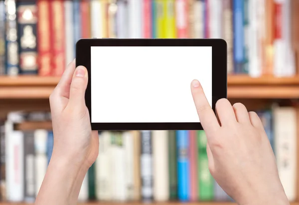 Finger touches tablet pc screen and bookcase — Stock Photo, Image