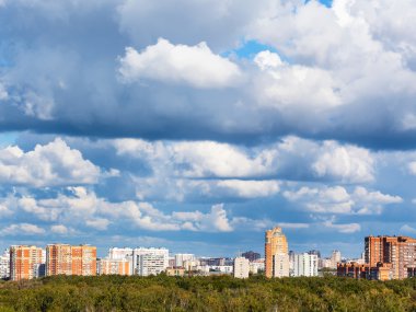 Yeşil orman ve şehir üzerinde düşük mavi bulutlar