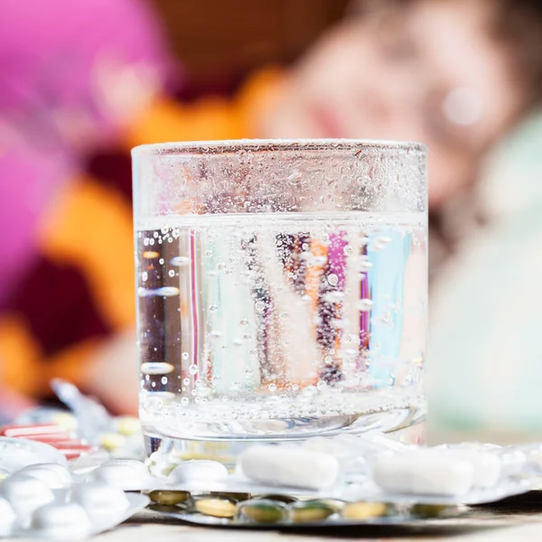 Glas mit aufgelöstem Medikament und Tabletten auf dem Tisch — Stockfoto