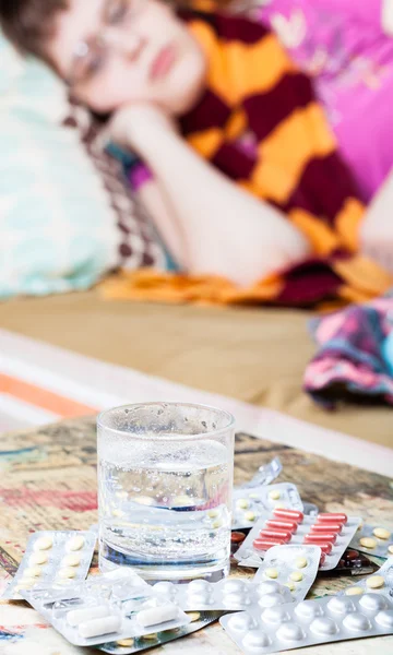 Glas med vatten och medikament på bord — Stockfoto