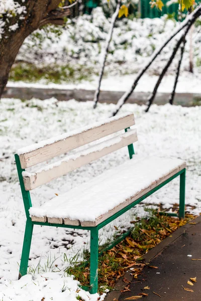 秋の市の公園のベンチで初めての雪 — ストック写真