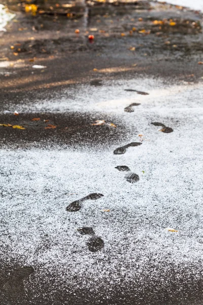 Pegadas no caminho molhado coberto pela primeira neve — Fotografia de Stock