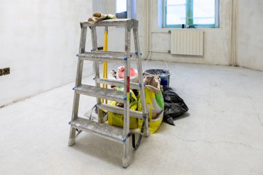 Merdivenler, aletler, inşaat malzemeleri beton odadaki çantalarda karışımlar ve şehir dairesinin yenilenmesi sırasında kaba bir şekilde bitirilmiş.