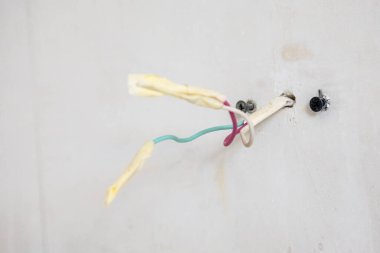 Yalıtımlı elektrik kabloları, şehir binasının yenilenmesi sırasında kaldırılan duvar lambasının sıva duvarından dışarı fırlıyor.