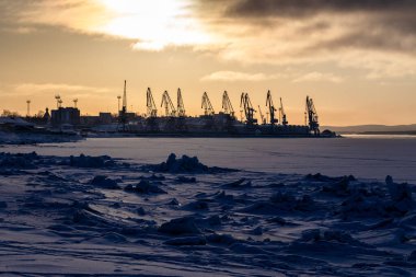 Şarap mevsiminde Rusya 'nın Murmansk Oblastı' na seyahat - Kandalaksha kasabasının limanında kış gündoğumunda karlı kıyı ve turnalar