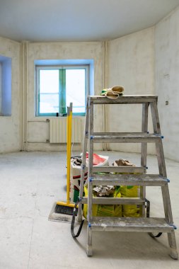 Merdiven, aletler, beton odada inşaat çantaları. Şehir dairesinin tadilatı sırasında sert bir şekilde tamamlanmış.