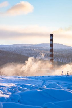 Şarap mevsiminde Rusya 'nın Murmansk Oblastı' na yolculuk. Kar yağışı ve kış gündoğumunda kazan dairesinin ısıtma sisteminin bacası.