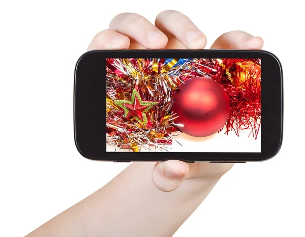 Hand holds smartphone with Xmas decorations — Stock Photo, Image