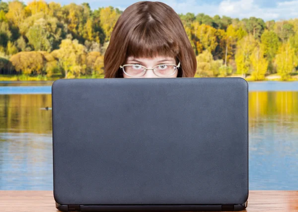 Dívka vypadá kryt notebooku a jezero v podzim — Stock fotografie