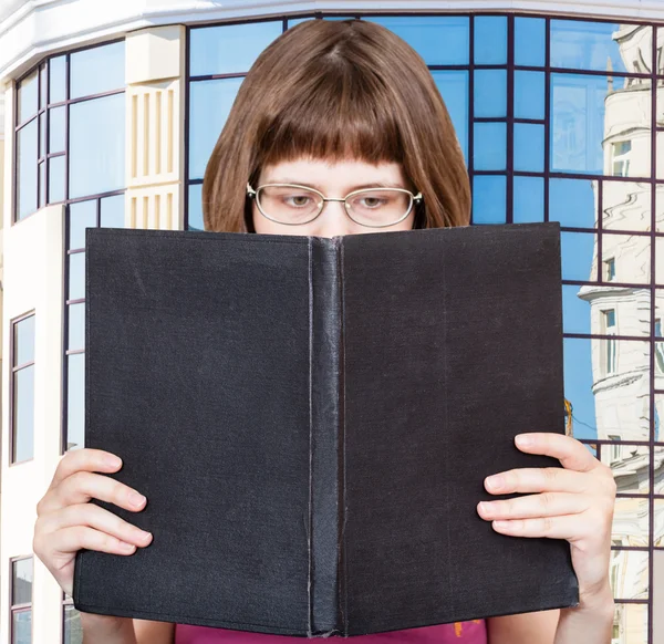 Girl reads big book and apartment house — Stock Photo, Image