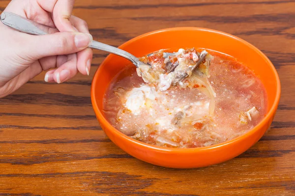 Hand hält Esslöffel mit Kohlsuppe über Schüssel — Stockfoto