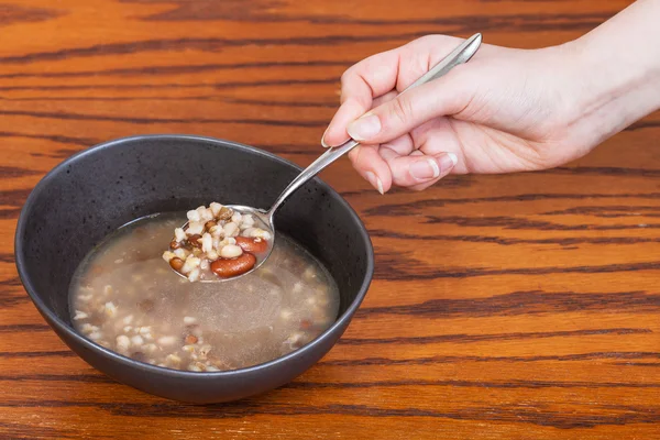 Hand hält Löffel mit Bohnen Suppe über Schüssel — Stockfoto