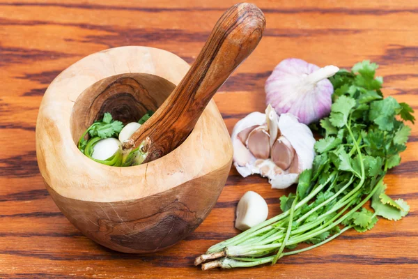 Ξύλινο Γουδί με χόρτο cilantro και το σκόρδο — Φωτογραφία Αρχείου